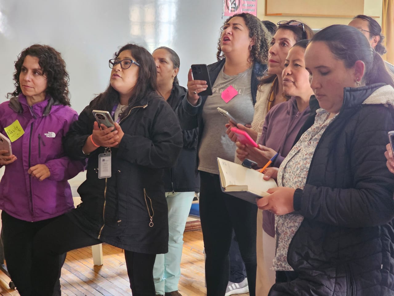 Grupo de mujeres participando en un taller de capacitación tecnológica de Fidepor, usando smartphones y aprendiendo habilidades digitales como parte de los programas de inclusión tecnológica